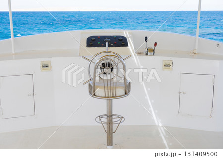 Nautical marine scene with sailboat steering wheel overlooking blue ocean horizon 131409500