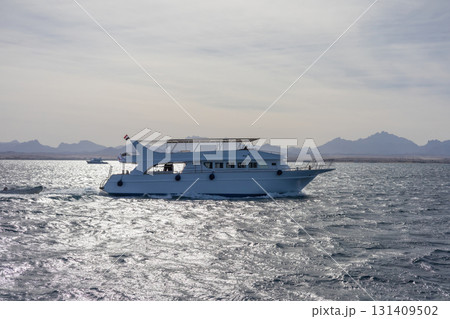 Serene ocean voyage with luxurious yacht against mountainous horizon 131409502