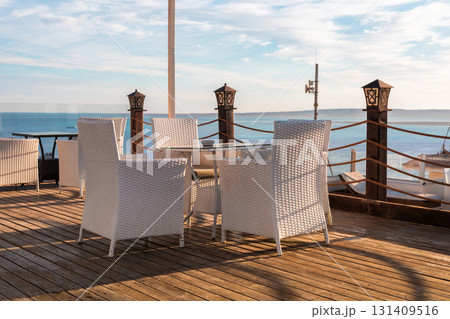 Seaside patio with white wicker chairs overlooking a tranquil ocean view 131409516