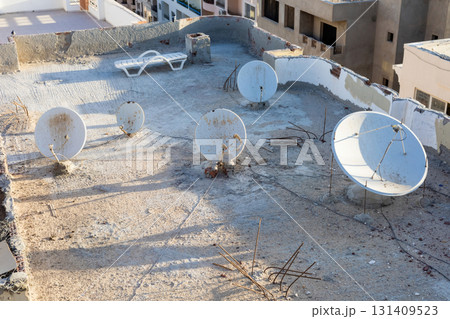 Urban rooftop with satellite dishes under clear sky 131409523