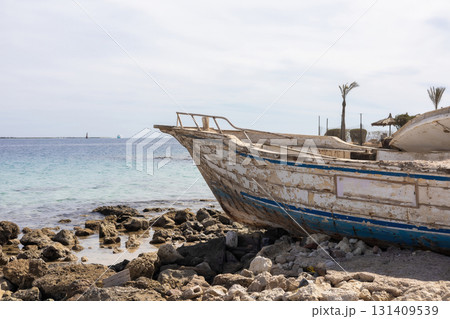 Weathered boat on rocky shore by a calm sea, evoking tranquility and nostalgia 131409539