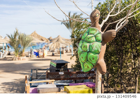 Tropical beach scene with vibrant turtle sculpture and relaxing atmosphere Tropical beach scene with vibrant turtle sculpture and relaxing atmosphere 131409546