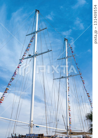 Majestic sailing ship masts with colorful flags against blue sky Majestic sailing ship masts with colorful flags against blue sky 131409554