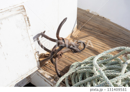 Vintage nautical anchor and rope on weathered wooden deck Vintage nautical anchor and rope on weathered wooden deck 131409581