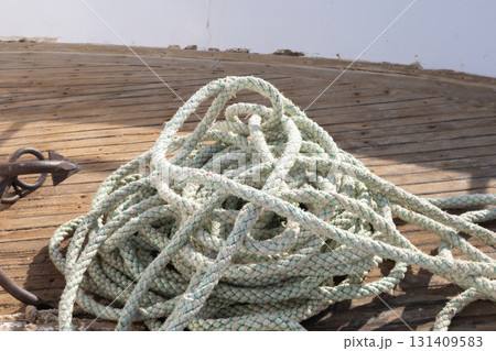 Nautical rope coil on weathered deck capturing maritime charm 131409583