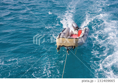 Inflatable dinghy towed on vibrant blue ocean waves for water adventure concept 131409665