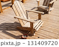 Rustic wooden adirondack chairs on sunlit deck for relaxation and outdoor leisure 131409720