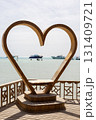 Heart-shaped sculpture overlooking tranquil sea with boats in the distance 131409721