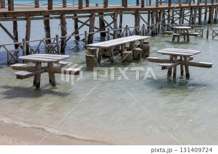 Tranquil seaside pier with wooden tables and crystal clear water for relaxation  131409724
