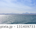 Tranquil coastal landscape with blue ocean and distant mountains under a clear sky 131409733