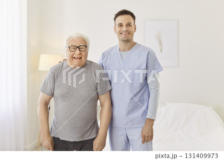 Portrait of happy health care worker with elderly man smiling and hugging in rehabilitation clinic 131409973