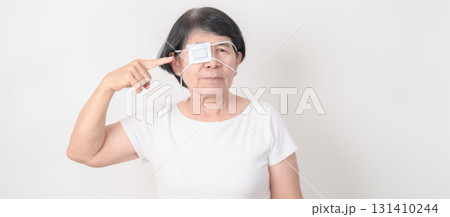 Elderly Woman with Eye protecting by Eye Pad for concepts of Eye disease, Cataract, Glaucoma, Age Related Macular Degeneration, Diabetic Retinopathy, Vitreous, Conjunctivitis, World Glaucoma day 131410244