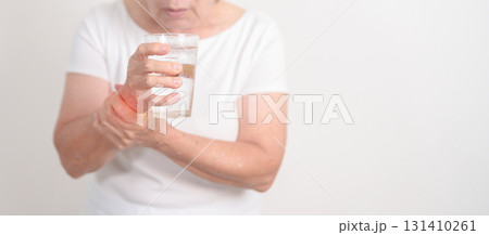 Elderly woman having Tremor hand during hold water glass. Parkinson disease April awareness month, Carpal Tunnel Syndrome, rheumatoid and brain injury, Neurological disorder and Senior health concept 131410261