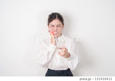 Business woman having toothache and pain after drink ice water for concept of Teeth Sensitive to Cold, Tooth Decay and Gum Disease, Grinding Teeth and Stress, Exposed Nerve Roots, Crack and Receding 131410411