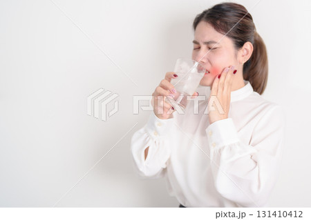 Business woman having toothache and pain after drink ice water for concept of Teeth Sensitive to Cold, Tooth Decay and Gum Disease, Grinding Teeth and Stress, Exposed Nerve Roots, Crack and Receding 131410412