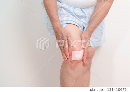 Elderly woman having knee ache with Medicated pain relief patch plaster to Runners Knee or Patellofemoral Pain Syndrome, osteoarthritis, arthritis, rheumatism and Patellar Tendinitis. Senior health Elderly woman having knee ache with Medicated pain relief patch plaster to Runners Knee or Patellofemoral Pain Syndrome, osteoarthritis, arthritis, rheumatism and Patellar Tendinitis. Senior health 131410671