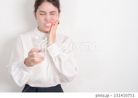Business woman having toothache and pain after drink ice water for concept of Teeth Sensitive to Cold, Tooth Decay and Gum Disease, Grinding Teeth and Stress, Exposed Nerve Roots, Crack and Receding 131410751