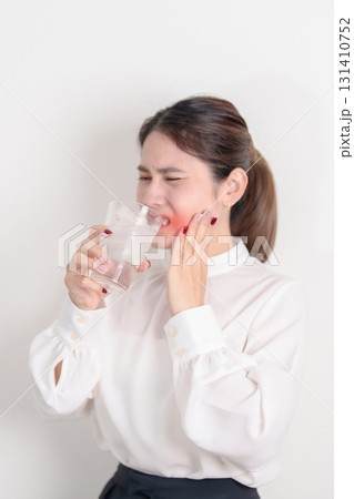Business woman having toothache and pain after drink ice water for concept of Teeth Sensitive to Cold, Tooth Decay and Gum Disease, Grinding Teeth and Stress, Exposed Nerve Roots, Crack and Receding 131410752