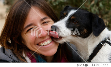 Smiling woman shares a joyful moment as her dog affectionately licks her cheek 131411667