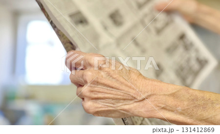 室内で新聞を持って広げる高齢者の手元_左向き 室内で新聞を持って広げる高齢者の手元_左向き 131412869