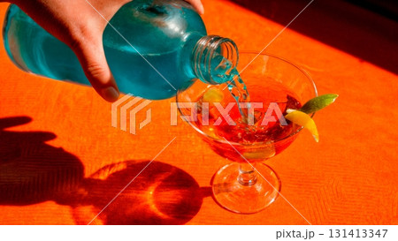 A vibrant, colorful cocktail being poured into a glass. Mixology, creative cocktails, bartender, party, celebration. 131413347