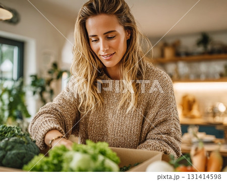 Woman unboxing fresh delivery of organic vegetables Woman unboxing fresh delivery of organic vegetables 131414598