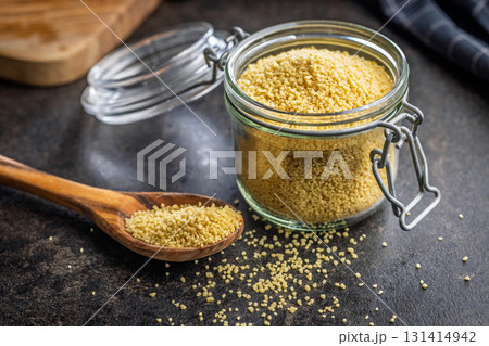 Raw couscous in spoon on black table. Raw couscous in spoon on black table. 131414942