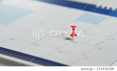 Close up of red pin placed on the 23rd day in a paper calendar, symbolizing organization, and appointment reminders 131416196