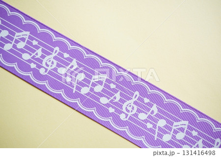 紫色のリボンに白い音符模様がデザインされたテープを斜めに撮影した写真。 131416498