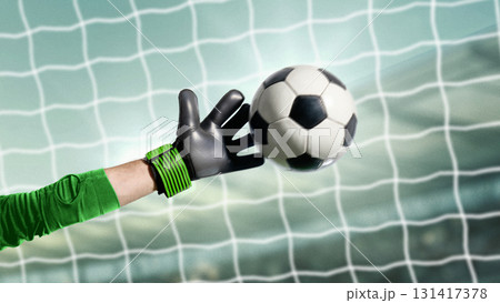 Goalkeeper in green uniform saving soccer ball with dramatic focus in front of net 131417378