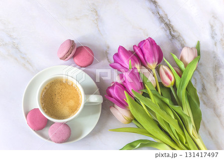 Top view for cup of coffee with macaroons and bouquet of pink tulips on a marbre background 131417497