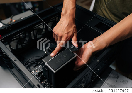 Close-up of technician hands installing CPU water cooler into desktop computer case, showcasing process of computer maintenance and upgrade. Concept of desktop PC maintenance and service. 131417997