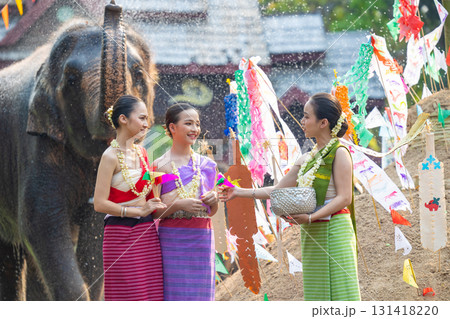 Songkran festival. Northern Thai people in Traditional clothes dressing splashing water together in Songkran day cultural festival with elephant background. Songkran festival. Northern Thai people in Traditional clothes dressing splashing water together in Songkran day cultural festival with elephant background. 131418220