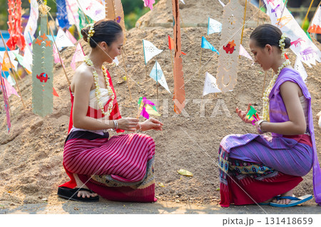 Songkran festival. Northern Thai people in Traditional clothes dressing carrying sand into temple to build sand pagoda and decoration with colorful paper flag. 131418659
