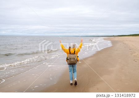 Attractive woman on windy cold beach. Beautiful tourist woman in stylish clothes enjoys life by sea. Attractive woman on windy cold beach. Beautiful tourist woman in stylish clothes enjoys life by sea. 131418972