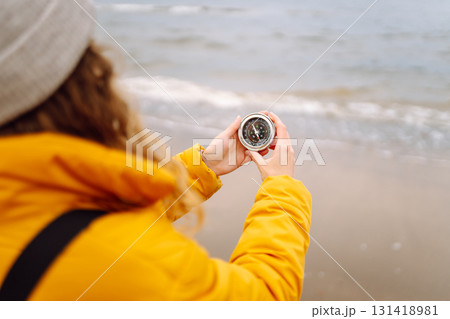 Woman traveler looking for directions with a compass on beach. Active lifestyle. Adventure concept. Woman traveler looking for directions with a compass on beach. Active lifestyle. Adventure concept. 131418981