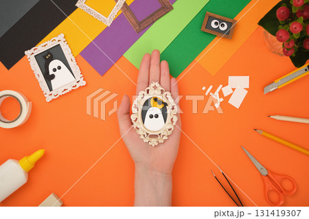 The finished paper craft. A portrait of a ghost with the silhouette of the moon and a bat in a frame. The finished paper craft. A portrait of a ghost with the silhouette of the moon and a bat in a frame. 131419307