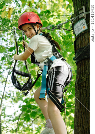Young Girl ziplining in climbing park, active summer adventure Young Girl ziplining in climbing park, active summer adventure 131419419