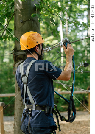 Man checking zipline equipment in forest rope park 131419433