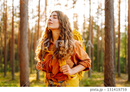Tourist woman hiking alone in thick autumn forest. Stylish female looks for pathway among trees. Tourist woman hiking alone in thick autumn forest. Stylish female looks for pathway among trees. 131419759
