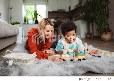 Mother and child playing with educational toys on rug 131420012
