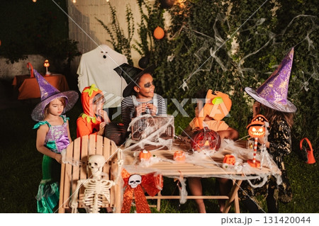 Children celebrating Halloween having fun together at a masquerade ball in the garden 131420044