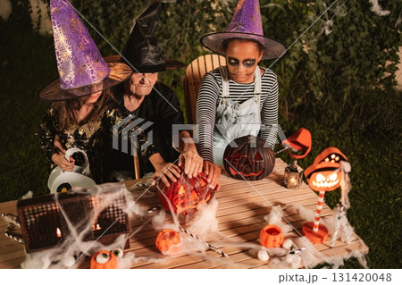 Family carving pumpkins for Halloween night party celebration 131420048