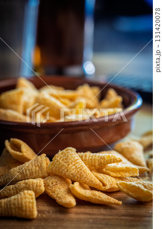 Bugles snack. Cone corn chips on wooden table. 131420078