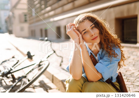 Beautiful smiling woman sitting next to bike on the street city. Adventure Concept 131420646