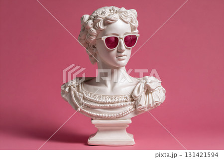Plaster bust of a Greek goddess wearing sunglasses on a pink background with copy space. 131421594