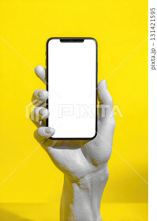 A smartphone with a blank white screen in the hand of a plaster statue against a yellow background. Blank, mockup, design template. 131421595