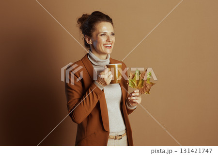 Smiling Businesswoman with Autumn Leaves and Cozy Mug 131421747