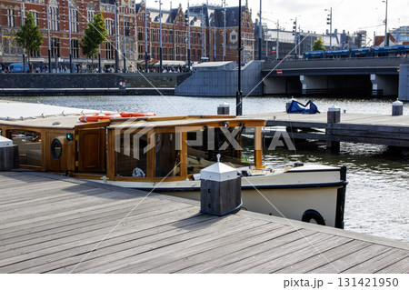 Tour Boat Docked by the Waterfront Near a Busy City Area in Amsterdam 131421950