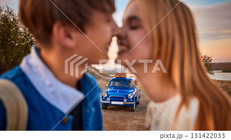 Romantic couple smiling close to each other with retro blue car in background Romantic couple smiling close to each other with retro blue car in background 131422033